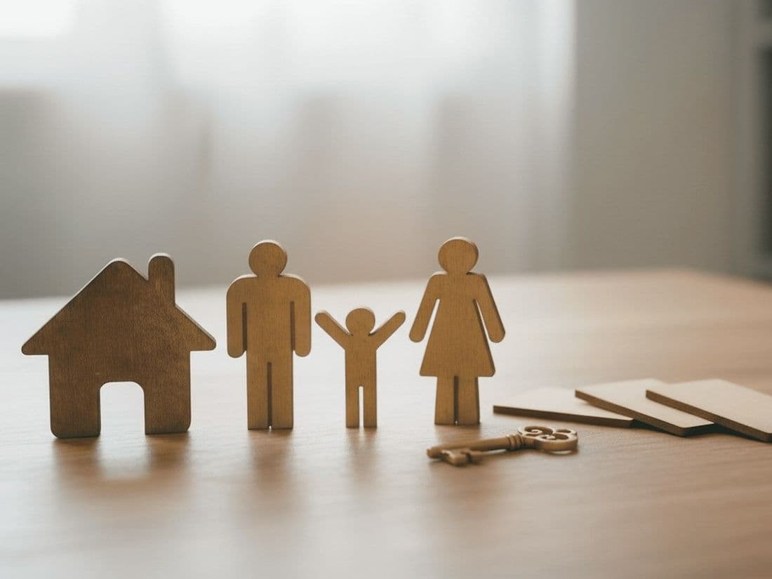 Figuras de madeira de uma família ao lado de uma casa e de chaves sobre a mesa