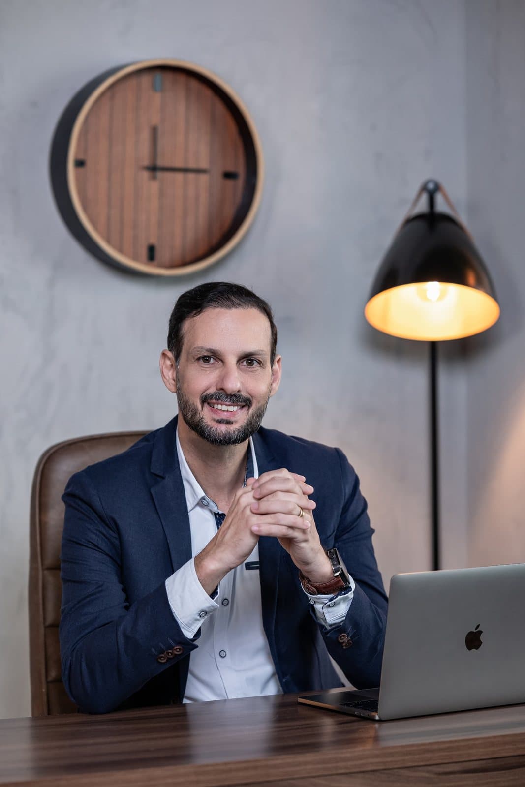 Davy Adame sorrindo à mesa, com um relógio na parede