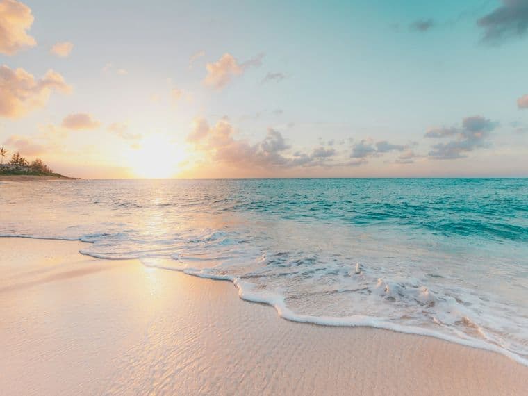 Praia ao pôr do sol, com ondas chegando à areia